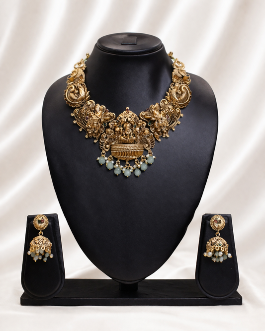 Gold necklace and earrings set on a black mannequin bust with a white background