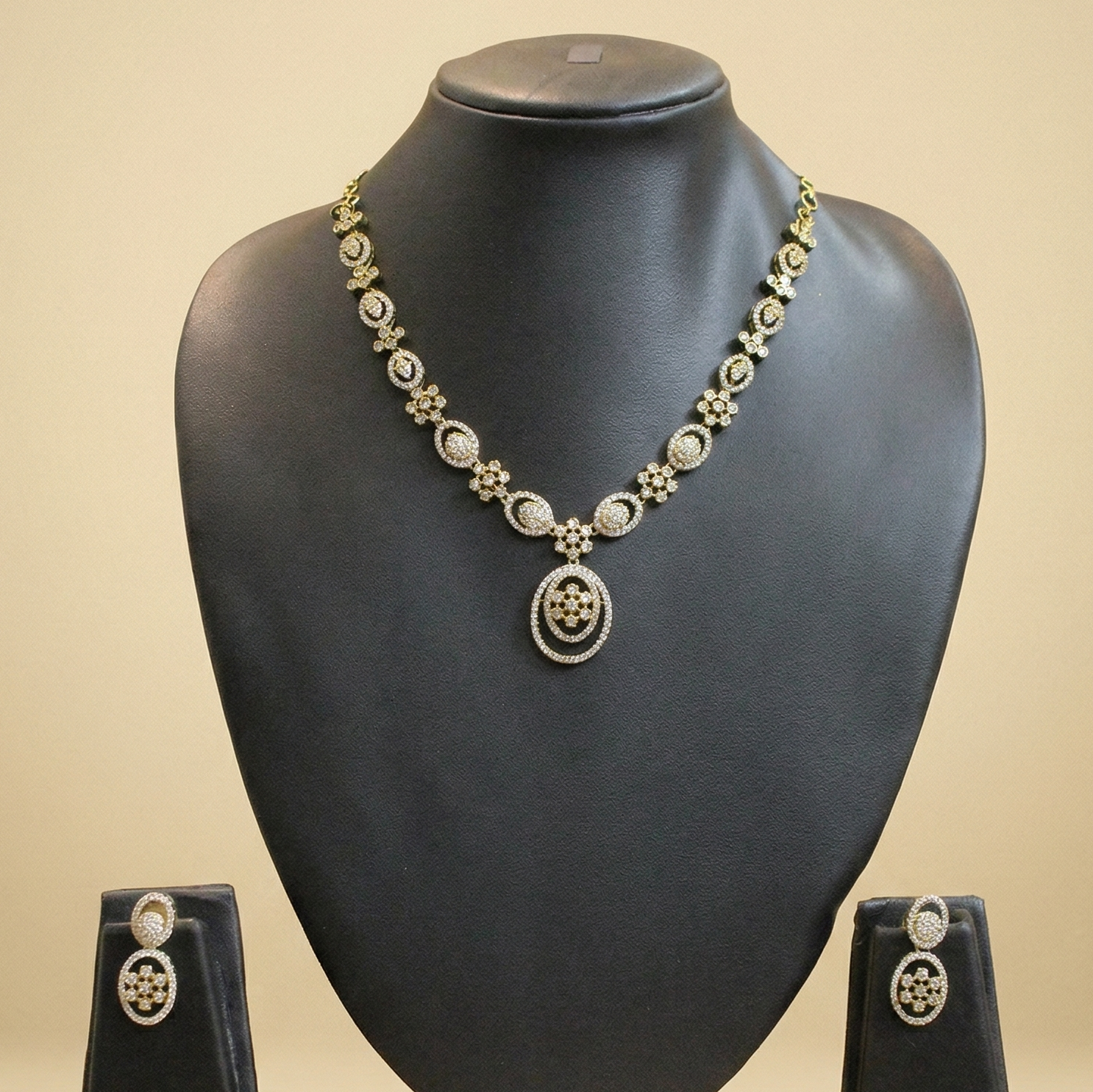 Jewelry set with necklace and earrings on a black mannequin bust against a beige background