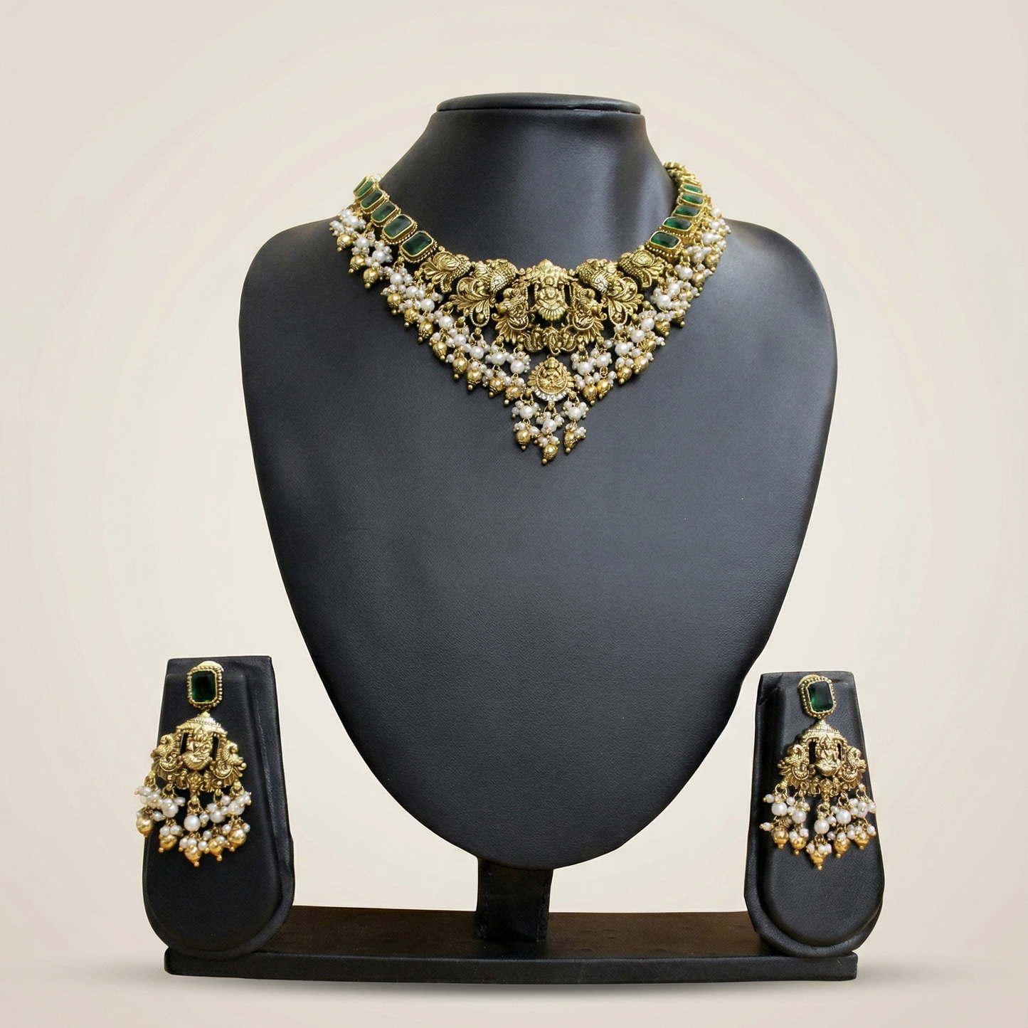 Jewelry set with necklace and earrings on a black mannequin bust against a beige background