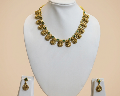 Gold necklace and earrings on a white mannequin bust against a beige background
