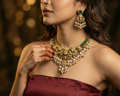 Woman wearing a gold necklace and earrings with a blurred background